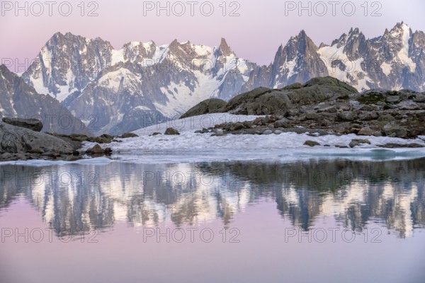 Evening mood with pink evening sky, mountain landscape at sunset, water reflection in Lac Blanc, mountain peaks, Grandes Jorasses and Aiguille du Midi of the Mont Blanc massif, Chamonix-Mont-Blanc, Haute-Savoie, France, Europe