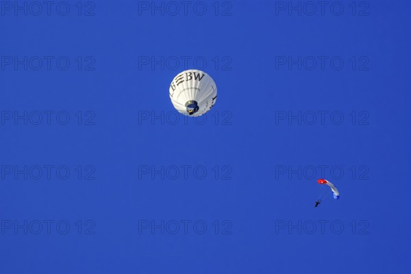 Landesbank BW hot air balloon and parachutist with open parachute in the air, as part of the aviation festival on the Rossfeld in Metzingen-Glems, Metzingen, Baden-Württemberg, Germany, 11 September 2010, for editorial use only, Europe