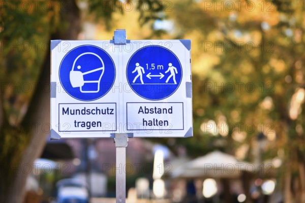 Signs for face mask and distance requirement in German city center with text saying wear face mask and keep distance
