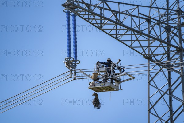 Construction of a new line route, 380 KV extra-high-voltage line between Osterath and Gohr, near Neuss, fitters in line trolleys, on the conductor cables, installing field spacers at great heights, North Rhine-Westphalia, Germany, Europe