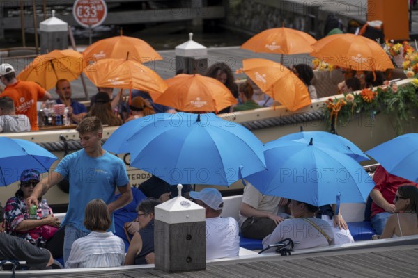 Canal cruise, with KINBoat and flagship organiser, canal boats decorated with flowers, passengers with umbrellas against the summer sun, heat, mooring at Centraal Station, excursion boat, Amsterdam Netherlands