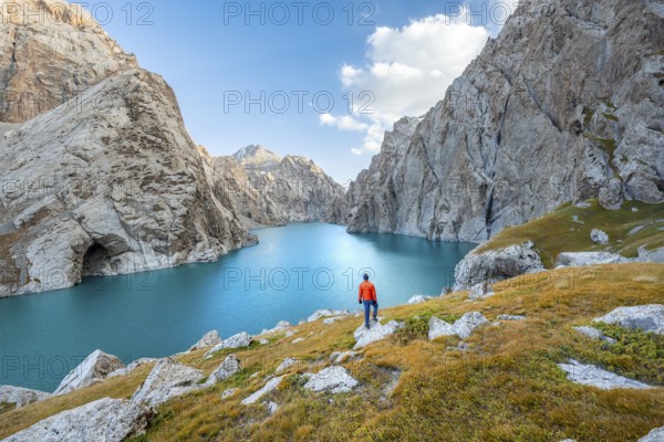 Young man at the turquoise mountain lake Kol Suu with rocky steep mountains, Kol Suu Lake, Sary Beles Mountains, Naryn Province, Kyrgyzstan, Asia