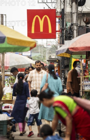 People walks by a McDonald's sign on October 26, 2024 in Guwahati, India. McDonald's recent food safety issues causing a 5% stock drop, after e-coli contamination in the United States