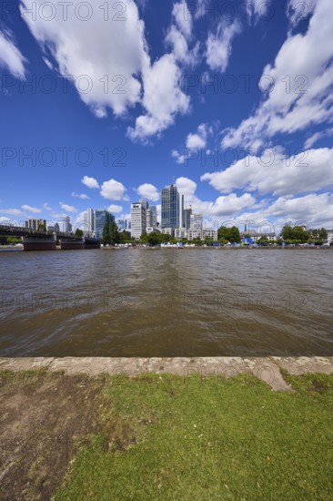 Skyline with riverbank, Main and skyscrapers under blue sky with cumulus clouds in Frankfurt am Main, Hesse, Germany, Europe