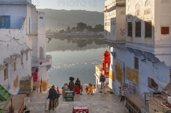 Morning atmosphere, people walking down to the lake shore, old town of Pushkar at the holy Pushkar Lake, Rajasthan, India, Asia