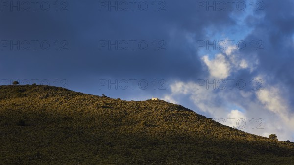 Sunlight and shadow play across a grassy hill under a dramatic sky with dense clouds, Lefka Ori, White Mountains, mountain massif, west, Crete, Greece, Europe