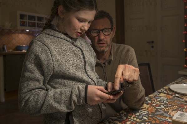 Father and daughter, 10 years old, looking for something with their mobile phone, Mecklenburg-Vorpommern, Germany, Europe