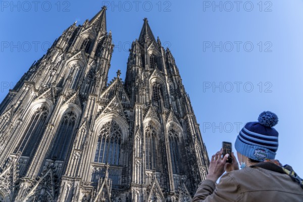 Cologne Cathedral, view of the west facade, at the north tower, tourist takes a photo with a mobile phone, Cologne, Germany, Europe