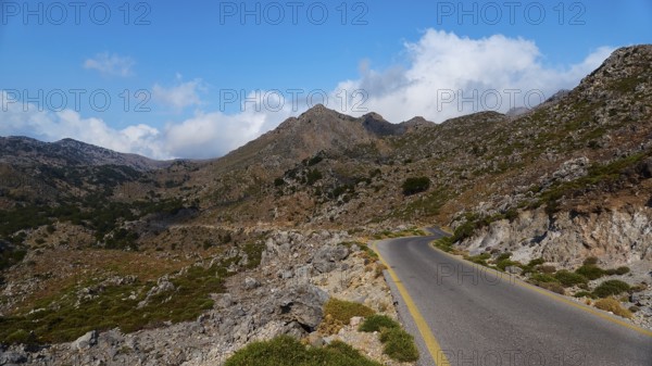 Asphalt road winds through a rocky mountain landscape under a blue, slightly cloudy sky, Kallikratis Gorge, Lefka Ori, White Mountains, mountain massif, West, Crete, Greece, Europe