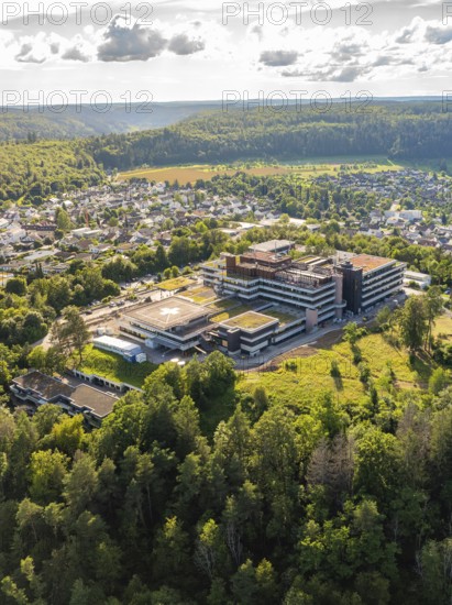 Large building surrounded by a green forest and town, seen from the air under a cloudy sky, hospital, Nagold, Black Forest, Germany, Europe
