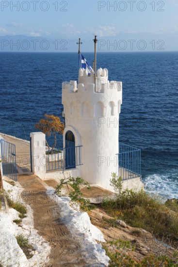 White tower on the coast with a Greek flag surrounded by the blue sea, Church of Agios Nikolaos Krasoktistos, Agia Kyriaki, Nafplio, Nafplio, Nafplion, Nafplion, Argolis, Argolic Gulf, Peloponnese, Greece, Europe