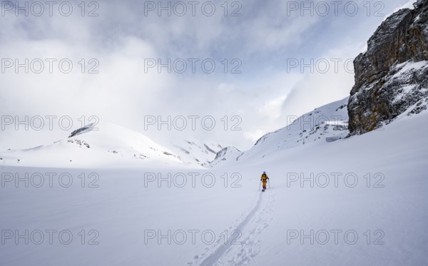 Lone ski tourer in snowy mountain landscape in the morning light, ascent to the Wildhorn, cloudy mood, high tour, Bernese Alps, Bernese Oberland, Switzerland, Europe