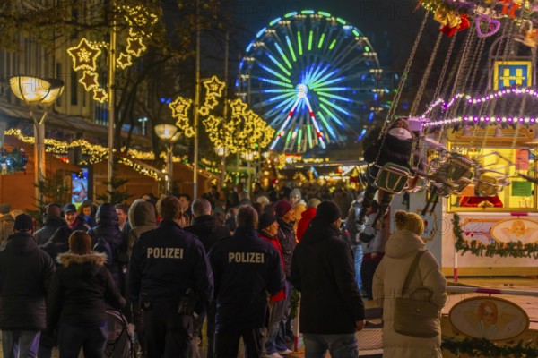 Christmas market on Königsstraße in the city centre of Duisburg, pre-Christmas season, Christmas lights, Ferris wheel, chain carousel, Christmas market stalls, crowds, North Rhine-Westphalia, Germany, police patrol, Europe