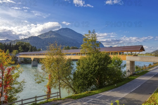 Landscape view of a wooden bridge over a river surrounded by autumnal nature and mountains, Inn footbridge, bridge over the Inn river
