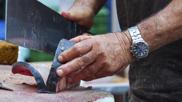Man cuts tuna into strips with large knife, fish market, old town, Catania, east coast, Sicily, Italy, Europe