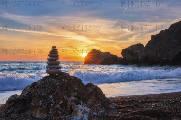 Concept of balance and harmony. Cairn stack of stones pebbles cairn on the beach coast of the sea in the nature on sunset. Meditative art of stone stacking