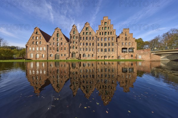 Historic salt warehouses with reflections on the water surface of the Trave, blue sky with veil clouds, Hanseatic city of Lübeck, Schleswig-Holstein, Germany, Europe