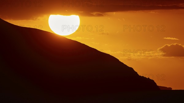 Sinking sun behind a mountain slope, intense orange light in the sky, sunset, Kassos, Karpathos, offshore islands, Dodecanese, Greek Islands, Greece, Europe