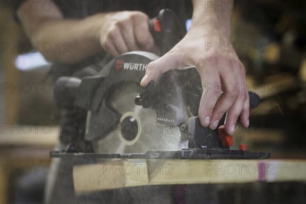 A man cuts wood with a hand-held circular saw. Berlin, 14.08.2024
