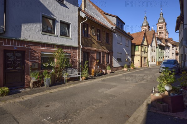 Residential houses with floral decorations, bench and the twin towers of Amorbach Abbey Church in Abteigasse in Amorbach, Lower Franconia, Miltenberg district, Bavaria, Germany, Europe