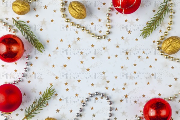 Frame made of Christmas decorations, fir branches, baubles, nuts on a white background with golden stars, copy room