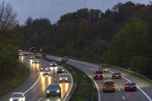 Cars driving on an illuminated motorway through a forest at dusk, Rems-Murr district, Baden-Württemberg, Germany, Europe