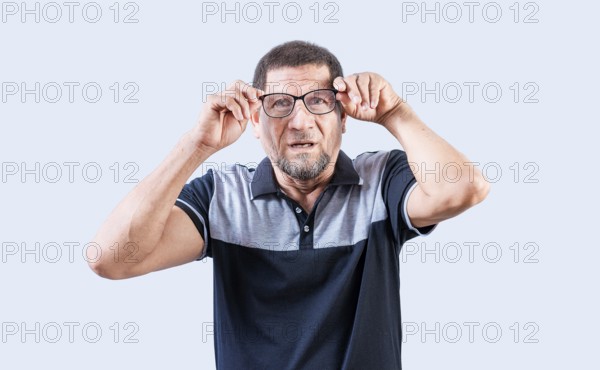 Surprised senior man taking off glasses looking at camera. Amazed senior man taking off glasses isolated