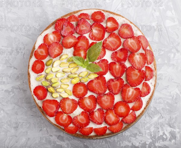 Homemade cake with yoghurt cream, strawberry and pistachio on a gray concrete background. top view. flat lay, close up
