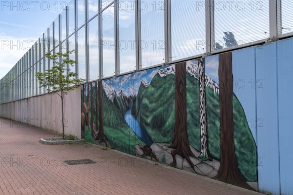 Noise barrier on Hombrucher Straße in Essen-Frillendorf, along the A40 motorway, 250 metres long, residents of a house have had a picture of a mountain lake painted on the grey concrete wall, as a more beautiful view, North Rhine-Westphalia, Germany, Europe