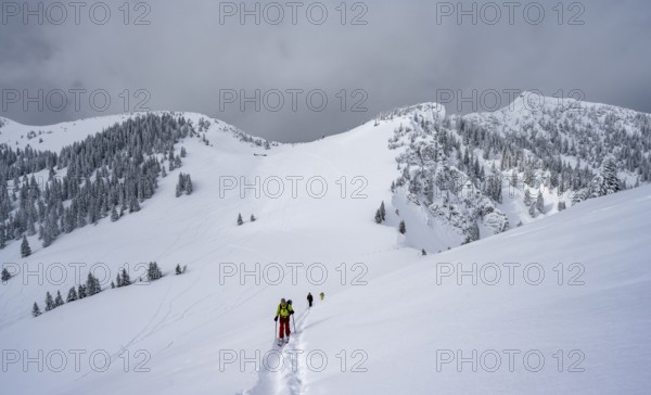 Ski tourers on the ascent to Raukopf, mountain landscape in the snow, mountain peaks Tanzeck and Aiplspitz, dramatic clouds, Mangfallgebrige, Bavaria, Germany, Europe