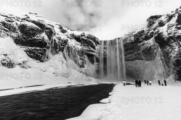 Skogafoss waterfall with icy and snowy rock face, black and white photo, Sudurland, Iceland, Europe