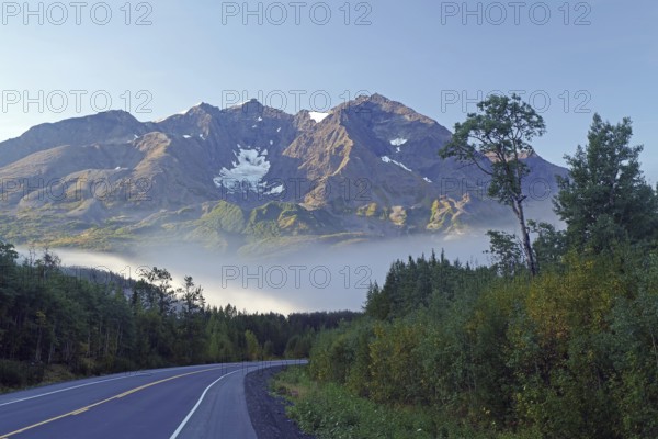 Traffic-free road, fog, foliage and snow-covered mountains, Richardson Highway, Alaska, USA, North America