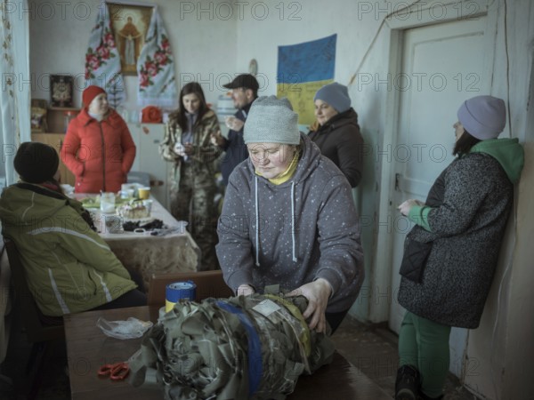 Women packing camouflage nets during a birthday party in the frontline village of Shevchenkove, Kharkiv Oblast, Ukraine, Europe