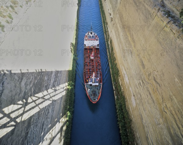 Aerial view of a red ship travelling through a narrow channel under a bridge, Corinth Canal, Corinth, Peloponnese, Greece, Europe
