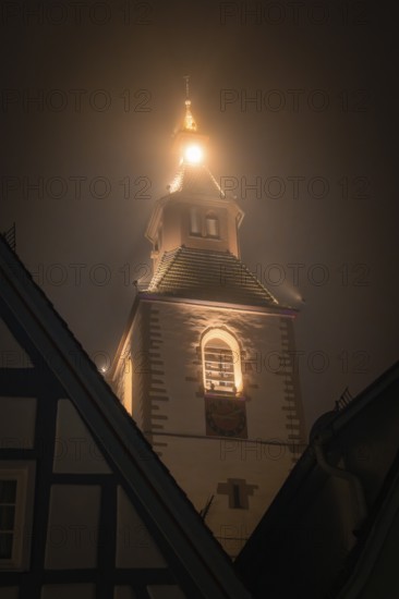 A church tower at night, shrouded in thick fog and illuminated by warm lights, Old Tower, Nagold, Black Forest, Germany, Europe