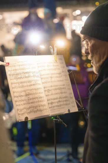 A musician on stage concentrates on his sheet music in the spotlight, Christmas market, Nagold, Black Forest, Germany, Europe