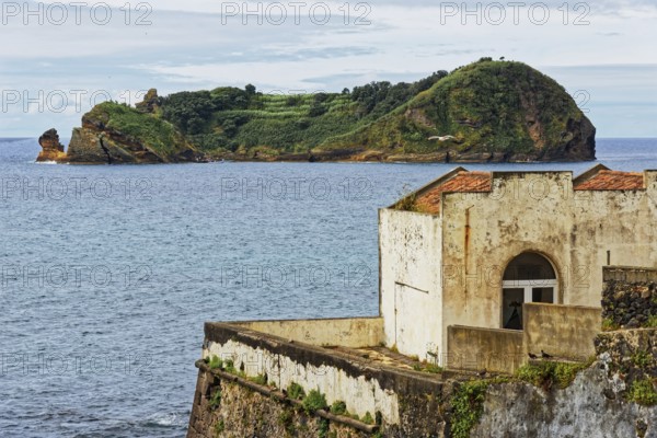 An old ruin on a rocky coast overlooking the sea and the small island and protected area of Ilhéu de Vila Franca do Campoin the distance, small town of Vila Franca do Campo, Sao Miguel, Azores, Portugal, Europe