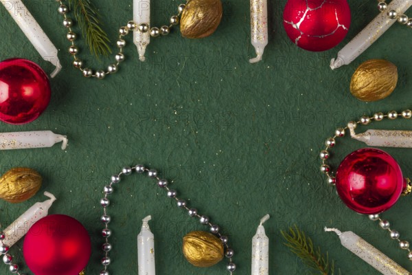 Frame made of Christmas decorations, candles, baubles, nuts on a green background, copy room