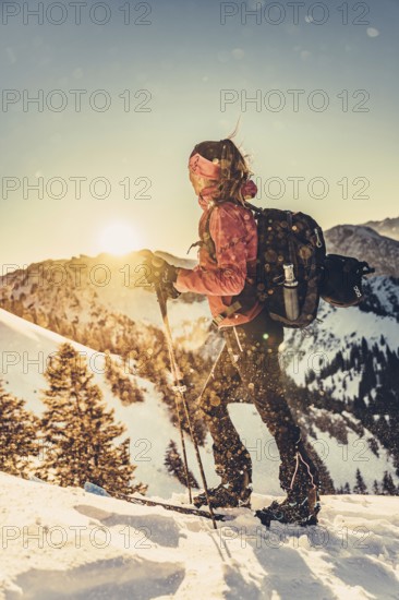A woman's ski tour at sunrise on the Tegelberg in the Allgäu in the Ammergebirge, Bavaria, Germany, Europe