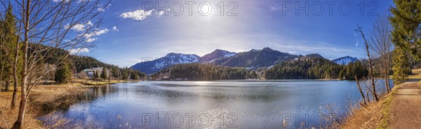 Large mountain lake with calm water surface, sunshine and picturesque mountain landscape, Spitzingsee