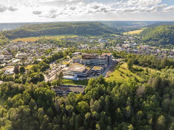 Aerial view of a building in the middle of a green forest, surrounded by an urban landscape under a cloudy sky, hospital, Nagold, Black Forest, Germany, Europe