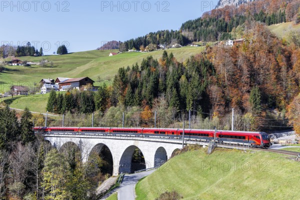 Railjet railway passenger train of the Austrian Federal Railways ÖBB on the Arlbergbahn in autumn in the Alps in Dalaas, Austria, Europe