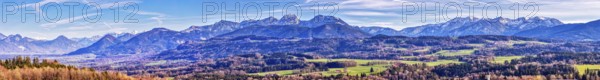 Expansive mountain landscape under a clear blue sky with few clouds and green fields, Irschenberg