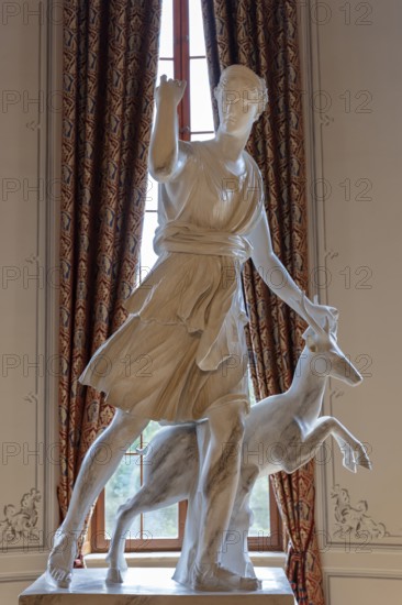 Classical statue in front of a window with decorative curtains, depicting a mythical figure, Rügen, Granitz Castle