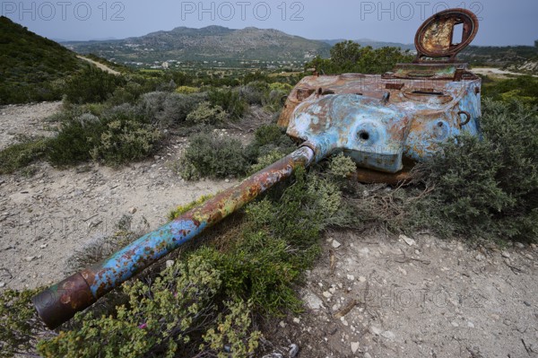A rusty tank lies in a green landscape, surrounded by bushes, Anthony Quinn Bay, Vagies Bay, Rhodes, Dodecanese, Greek Islands, Greece, Europe