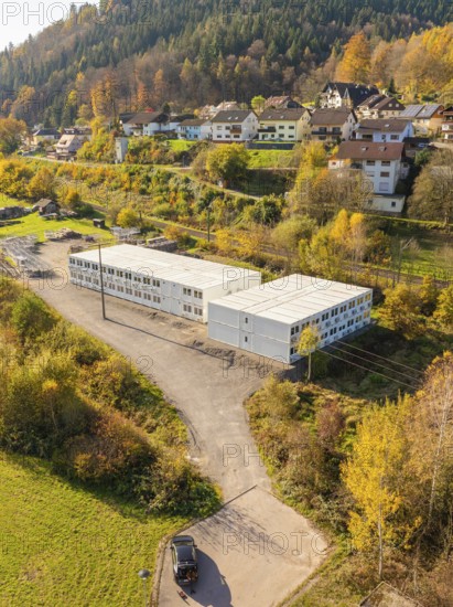 Autumn landscape with buildings and containers in the foreground, surrounded by colourful foliage, refugee accommodation Beermiß, Calmbach, Black Forest, Germany, Europe