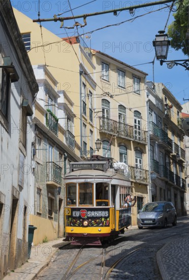 Yellow tram runs through narrow streets with historic buildings under a blue sky, Tram, Line 28, Carros eléctricos de Lisboa, Eléctricos de Lisboa, Old Town, Lisbon, Portugal, Europe