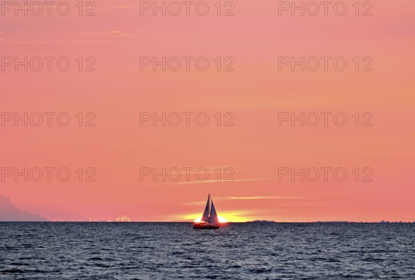 Sailboat sailing in the evening towards the setting sun, Baltic Sea, Poel Island, Mecklenburg-Western Pomerania, Germany, Europe