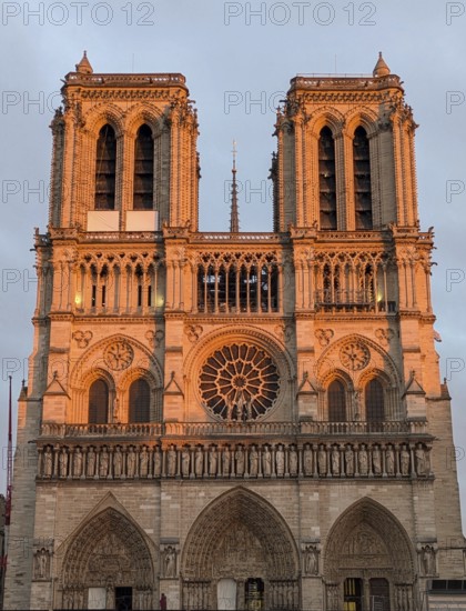 The facade of Notre Dame Cathedral glowing in the warm light of sunset. Paris, France, Europe