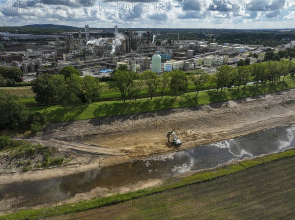 Oberhausen, North Rhine-Westphalia, Germany, renaturalisation of the Emscher in the Holtener Bruch. A new floodplain landscape for flood protection and biodiversity is being created here. In the background OQ Chemicals plant Ruhrchemie. The Emscher, which is currently straightened, is given curves again and can meander through its new floodplain. The ecological reorganisation of the Emscher system consists of the construction of a central wastewater treatment system in the Ruhr area, the construction of sewers and the renaturation of the Emscher and its tributaries. Following the construction of a parallel sewer, the Emscher has been completely free of sewage since January 2022. The river was previously an open, above-ground combined sewer with rainwater and wastewater, Europe